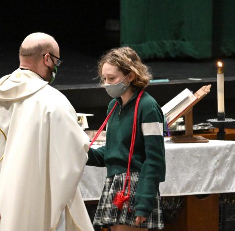 Father Danny Grover presents the red cord to senior Maddie Rowlan at the April 27 Mass.