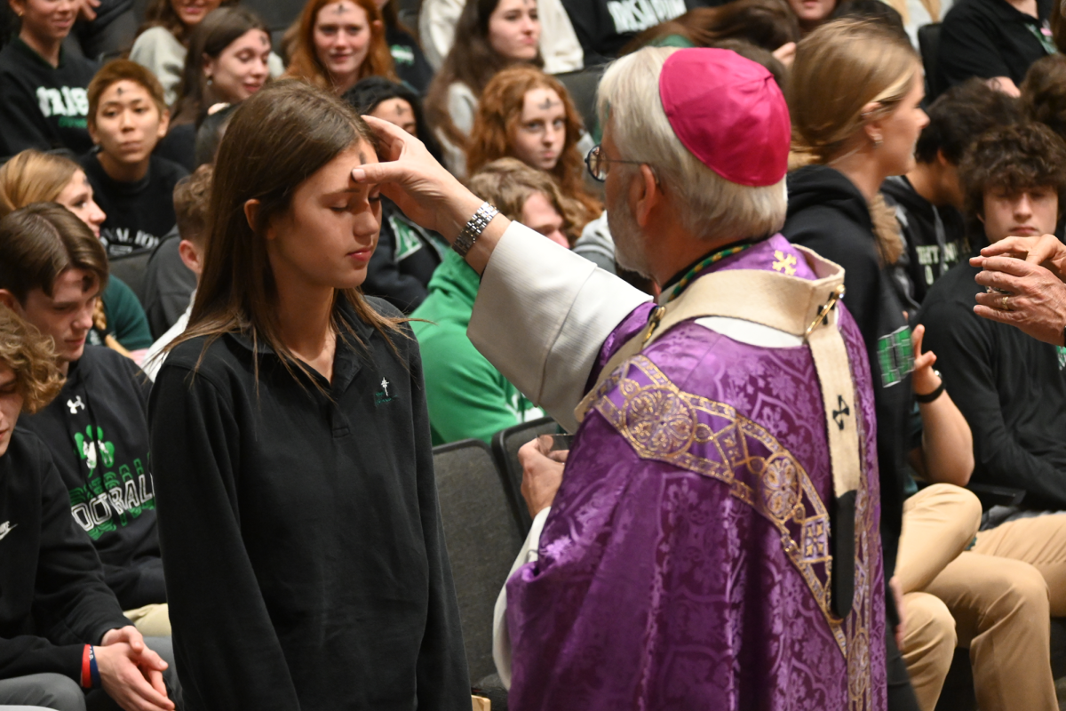 Archbishop Paul Coakley applies ashes on senior Allie Scholze's head on Ash Wednesday.