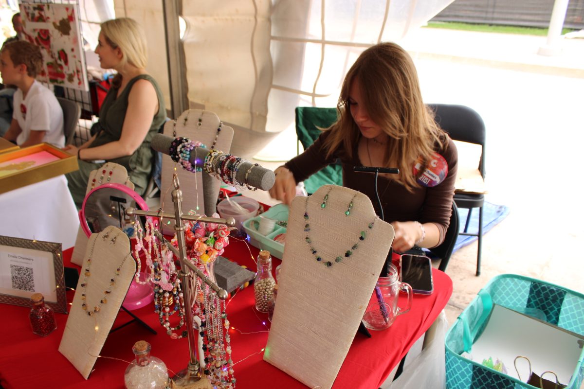 Junior Emelia Chambers works on a new piece while selling her handmade jewelry at the OKC Arts Festival.
