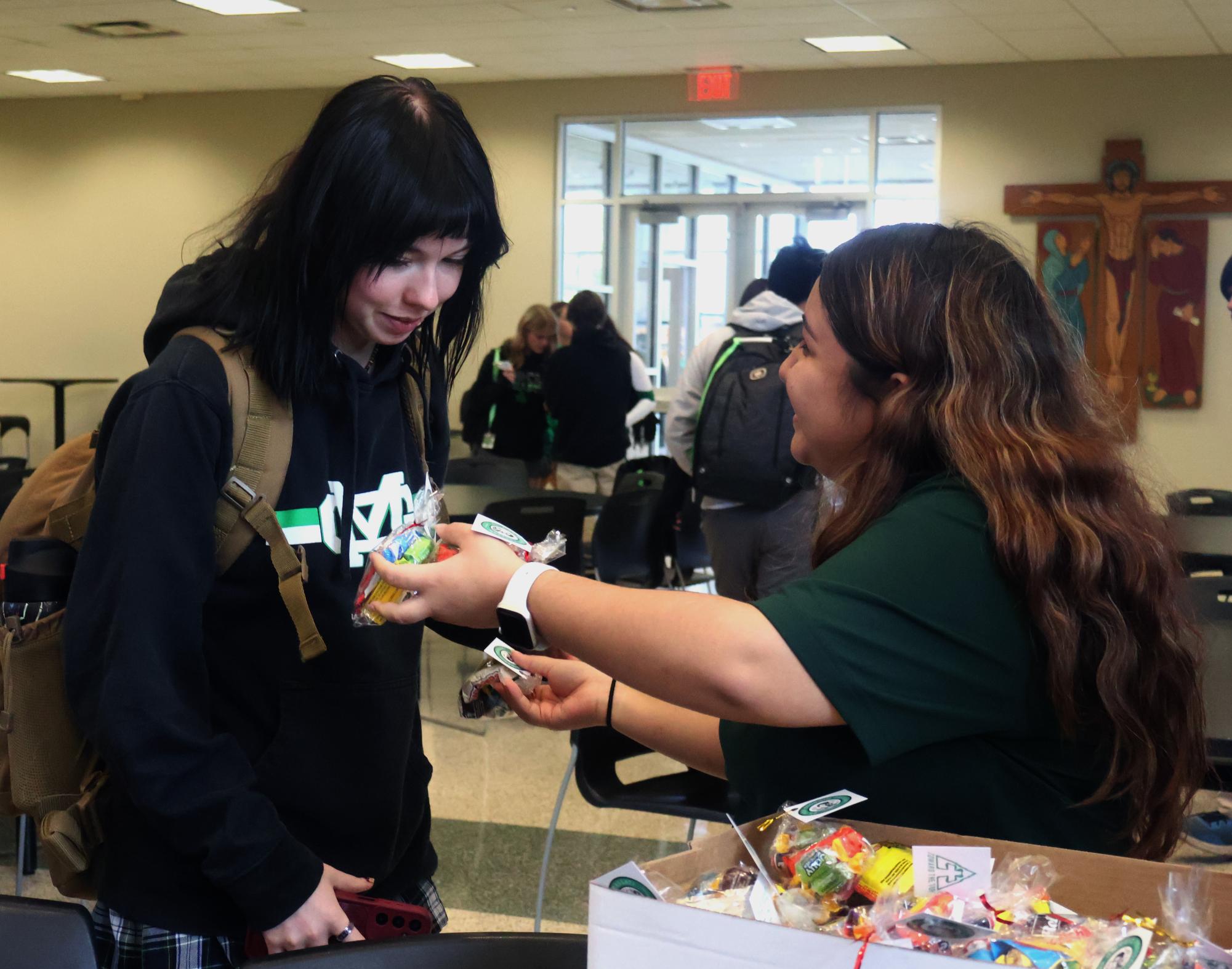 Senior Britney Gamez hands a candy bag to her classmate Meagan Coomes in celebration of Pier Giorgio Frassati’s canonization. 