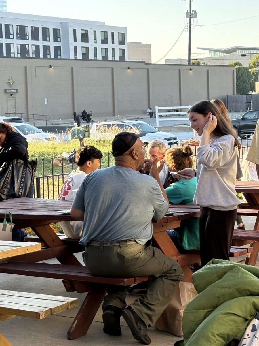 Senior Sophia Hart shares a conversation with a man at Sister BJ’s Pantry. Photo courtesy of Gia-luc Nguyen