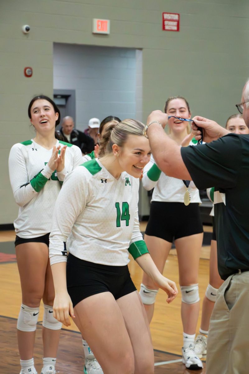 Senior Morgan St. John receives her medal from assistant athletic director Steve McCarthy