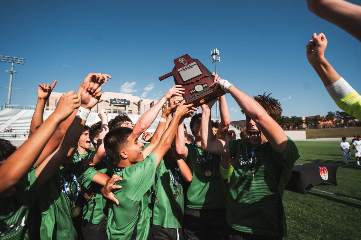 The Boys Soccer team cheers with their State Championship trophy.